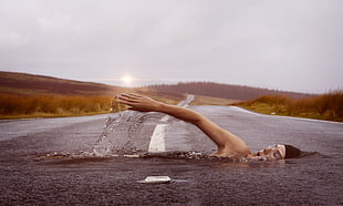 person swimming on asphalt road edited photo HD wallpaper