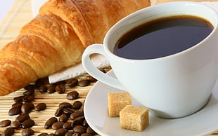 food photography of white ceramic mug with black coffee with two brown sugar cubes beside cooked pastry
