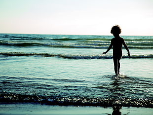silhouette photography of child on seashore under blue sky