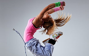 photography of woman jumping in pink tank top and purple sweatpants