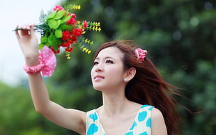 selective focus photography of woman in white and blue dress holding bouquet of flowers
