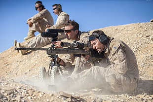 man holding sniper rifle beside man holding range finder near two men HD wallpaper