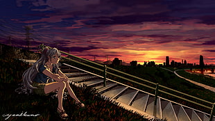 woman sitting on green grass while waiting for someone during sunset