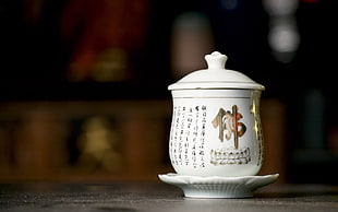 shallow focus photography of white ceramic cup kanji text and white lid