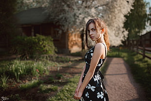 woman wearing black and white floral sleeveless dress standing on grass field