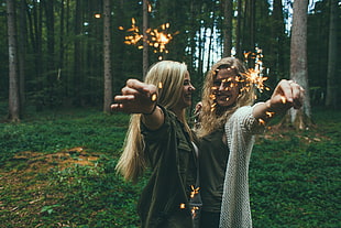 two women holding fireworks in forest during daytime