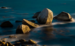 photo of rocks on body of water during daytime HD wallpaper