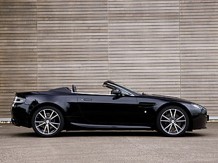 shallow focus photography of black convertible parked beside brown wooden wall