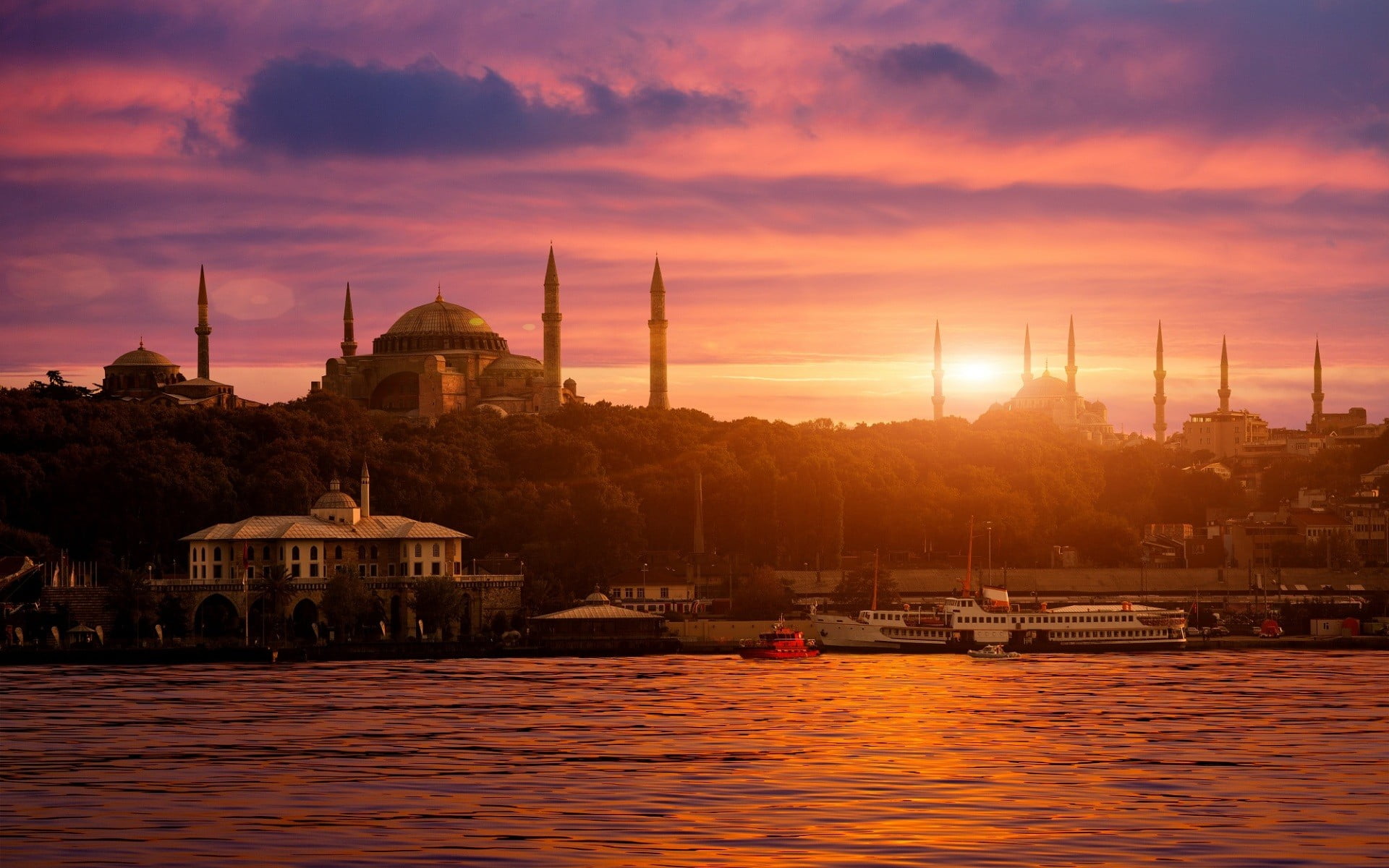 mosques near buildings and body of water during golden hours