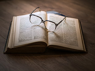 black-framed eyeglasses on top opened book