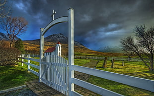 photography of white wooden gate under black clouds