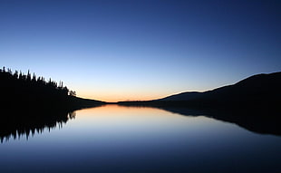 silhouette of mountain between lake HD wallpaper