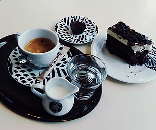 sliced chocolate cake and coffee on white and black ceramic plates