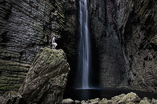 man standing on rock cliff near waterfalls HD wallpaper