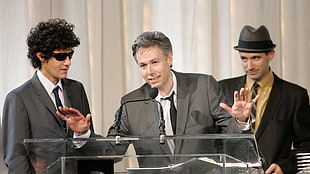 three man wearing black suit jackets on stage
