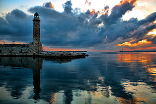 brown lighthouse near body of water under white skies HD wallpaper