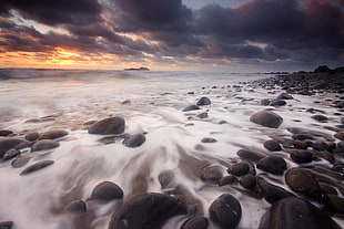 timelapse photography of ocean with rocks during golden hour