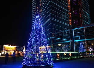 Christmas tree with blue string lights outside near building