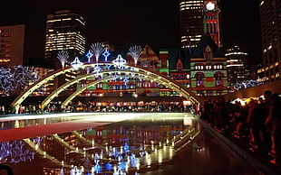 photography of lighted arch over body of water surrounded by people during nighttime