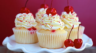 four cupcakes with cherries