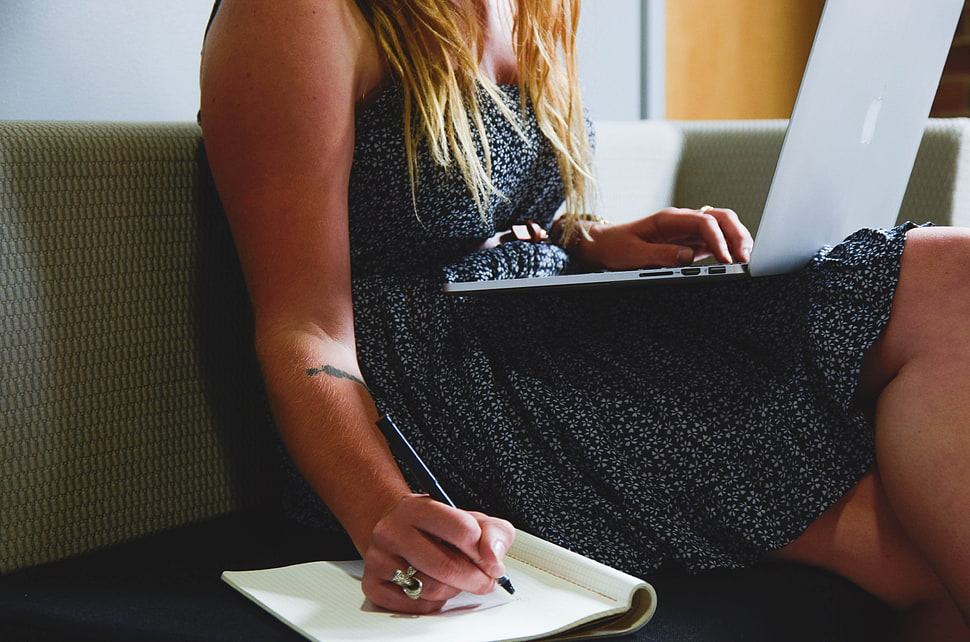 closeup photo of woman sitting in the sofa writing in the notebook HD wallpaper