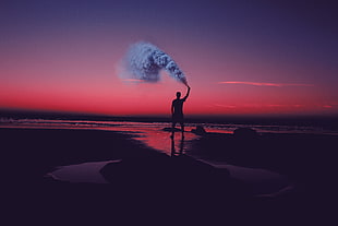 man standing white holding smoke screen during sunset