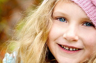 girl in pink knit cap smiling closeup photography