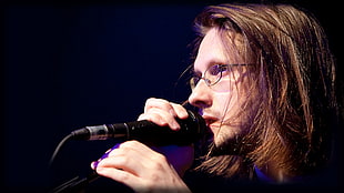 man wearing eyeglasses holding microphone