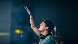 person in green shirt with black snapback and black headphones performing during daytime HD wallpaper