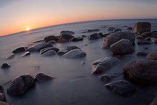 brown rock beside seashore during sunset