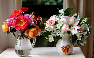 two red, orange, and white petaled flower arrangements on white vases