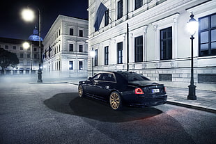 selective color photography of black sedan near buildings