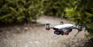 selective focus photography of white and grey drone quadcopter beside tall trees at daytime HD wallpaper