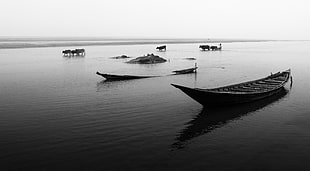 brown wooden boat on body of water in gray scale photo