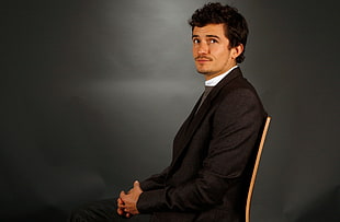 man in black blazer sitting on brown chair