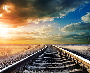 train tracks over ocean under blue and cloudy sky at sunset HD wallpaper