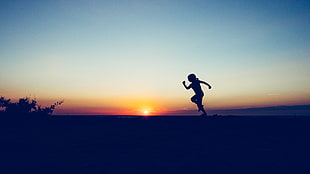 silhouette of person running on hill during sunset