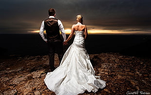 man in brown vest and white dress shirt holding hands with woman in white strapless wedding gown