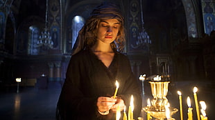 woman wearing black holding candle