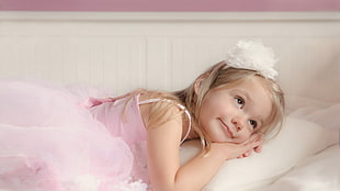 girl wearing pink dress lying on pillow inside room HD wallpaper