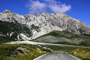 asphalt road between open grass field with snow-capped mountain range in background during daytime HD wallpaper