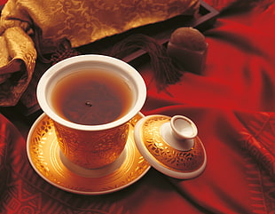 closeup photo of brass-colored and white ceramic cup filled with tea