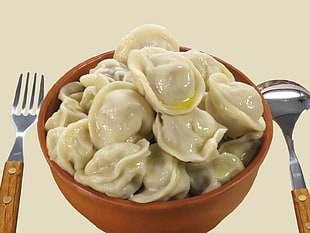 dumplings served on round brown bowl with spoon and fork