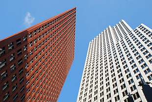 worms eye view of brown and white high rise building under blue and white cloudy sky during daylight