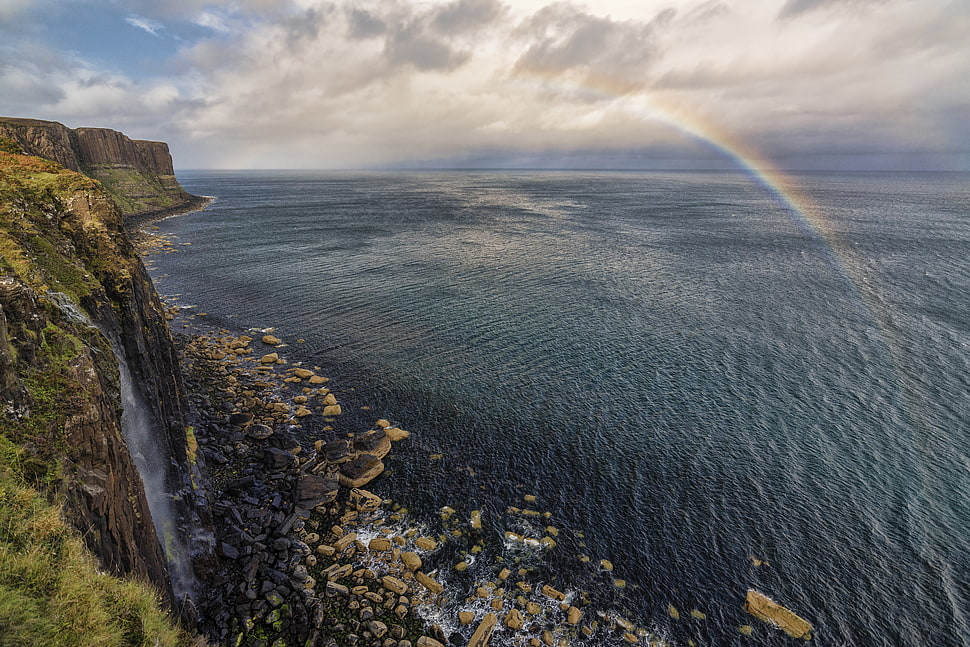 cliff near on ocean under cloudy sky HD wallpaper