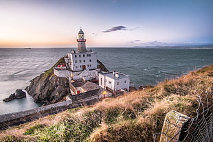 photo of lighthouse beside white painted building, baily lighthouse, dublin, ireland