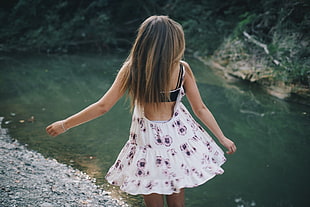 woman backless dress standing beside body of water