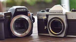 black Sony CX 350 camera beside gray Praktica MTL 5 camera on brown wooden surface