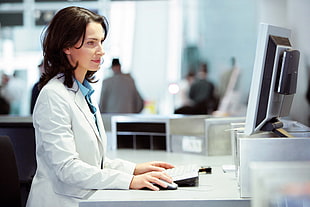 woman wearing white lab coat in front of computer screne