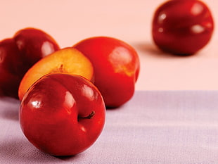photography of red apple fruits on white surface
